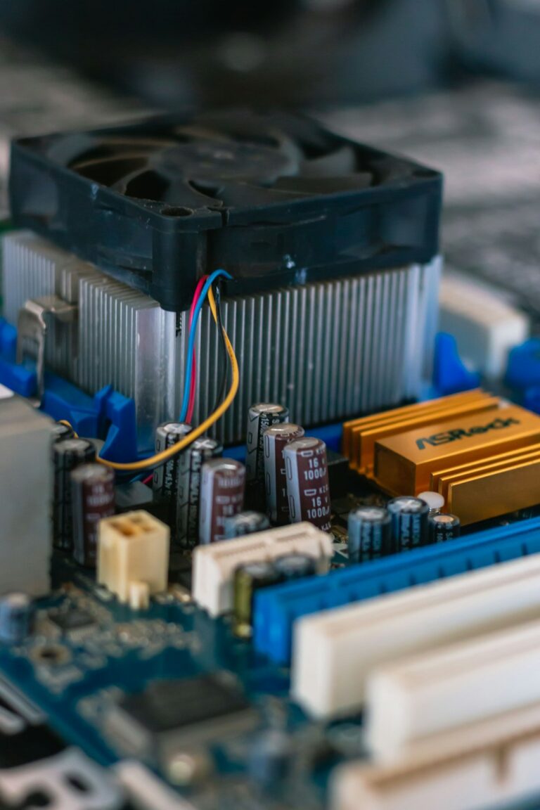 Close-up view of a computer motherboard with various components including capacitors, heatsinks, and a cooling fan.