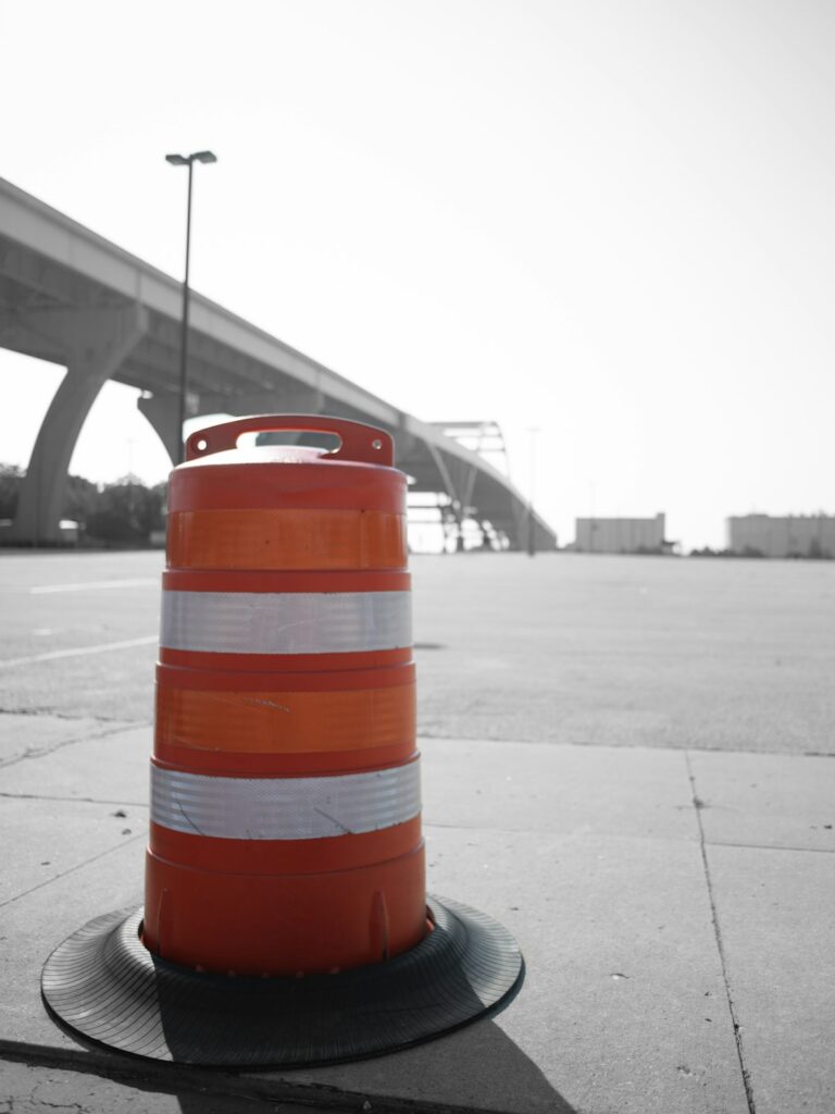 Orange construction barrel under a bridge on a sunny day