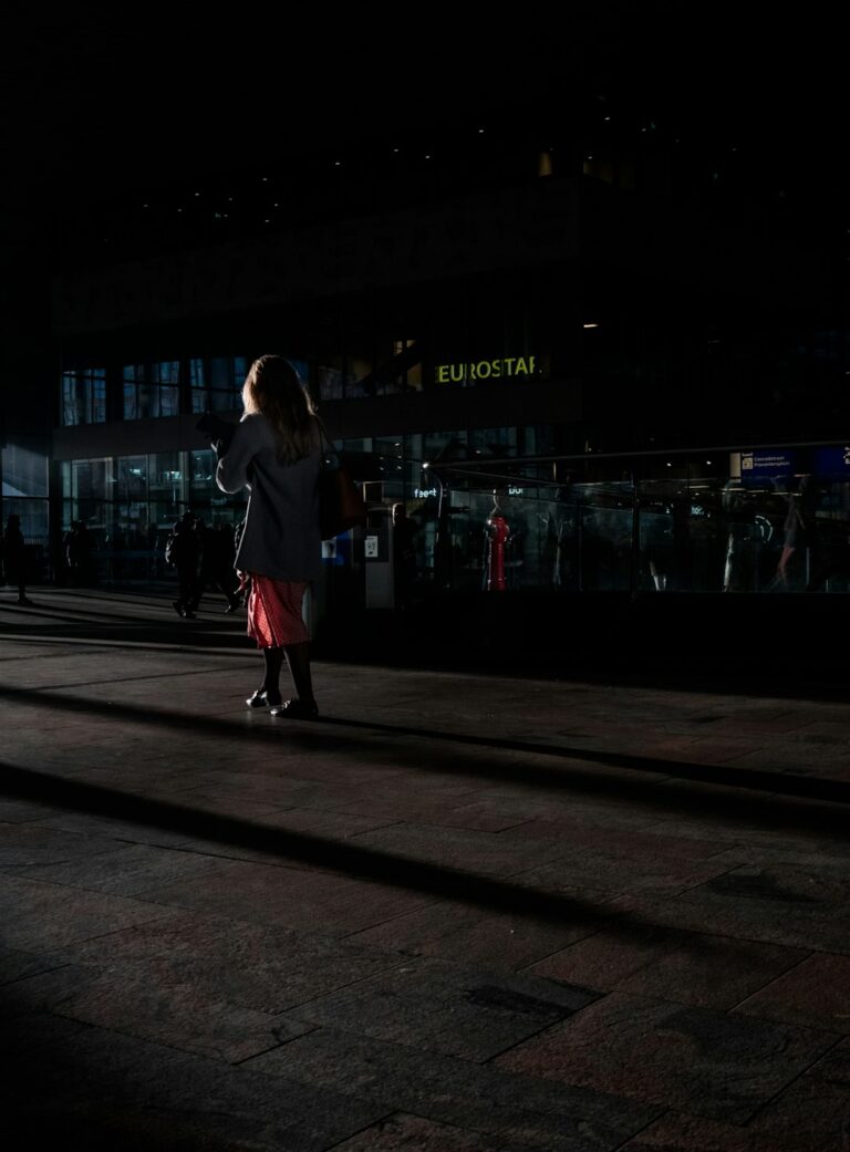 Person walking near Eurostar station in the evening with shadows and dim lighting.