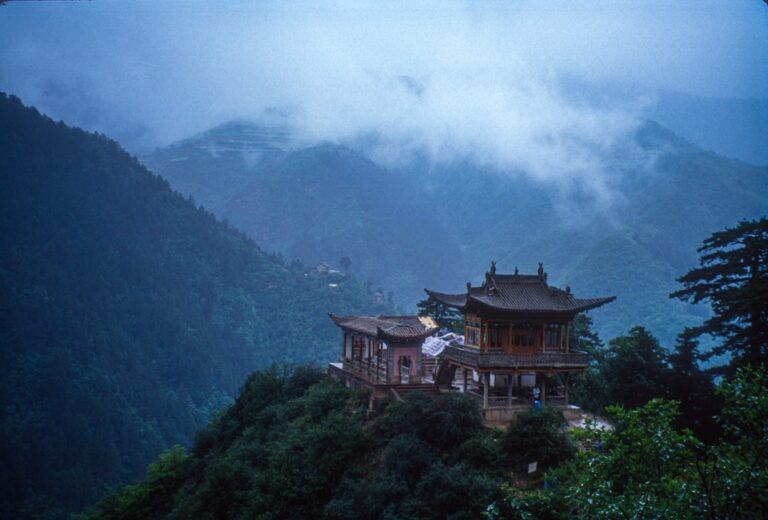 Traditional Asian building atop a foggy, mountainous landscape