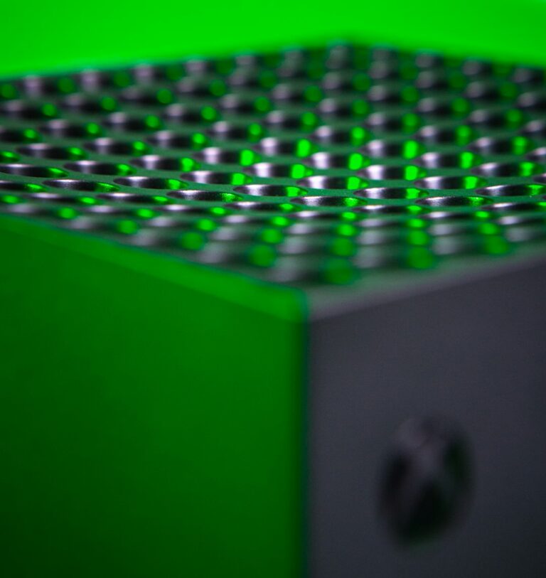 Close-up view of the top vent of a Microsoft Xbox Series X console illuminated with green light