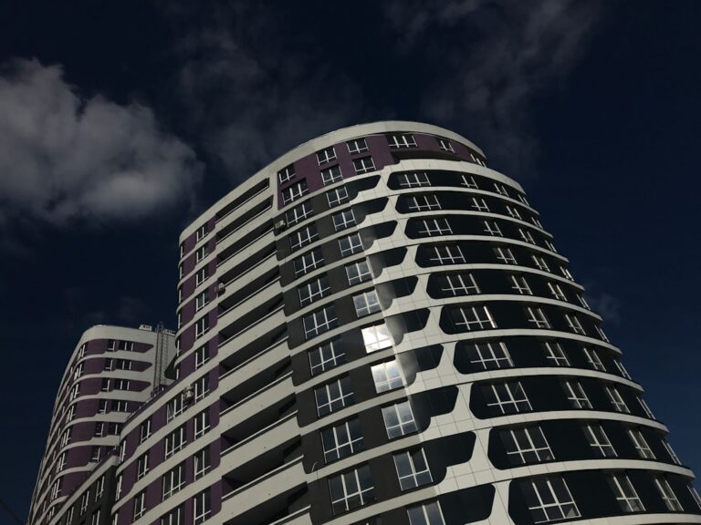 High-rise modern buildings with curved designs against a dark, cloudy sky, showcasing architectural expertise