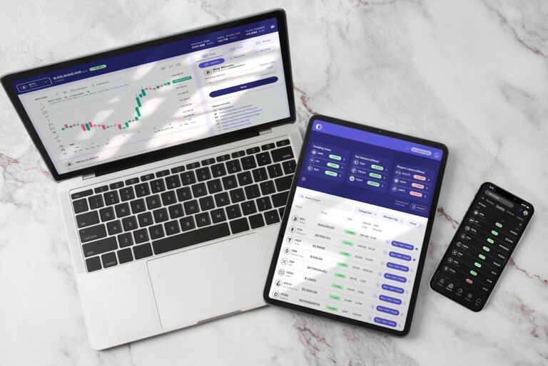 Three devices showcasing a trading and market trends application: laptop, tablet, and smartphone on marble surface.