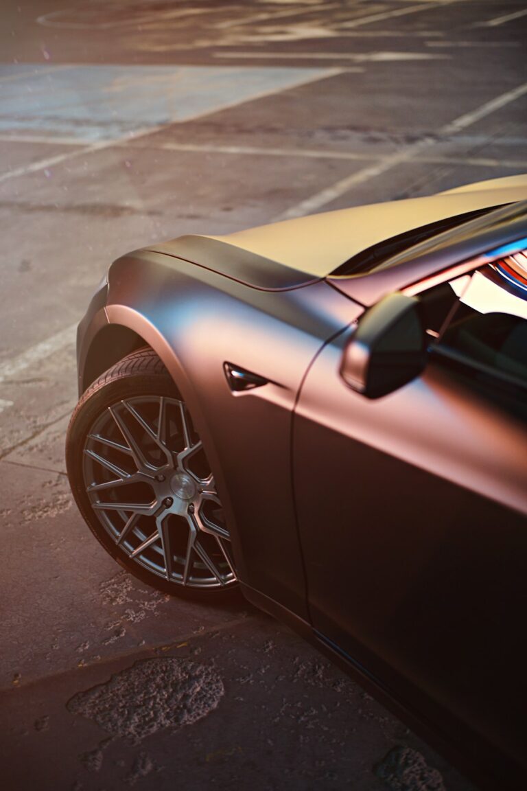 Close-up shot of a Tesla Cybertruck wheel and fender, parked in an urban area.