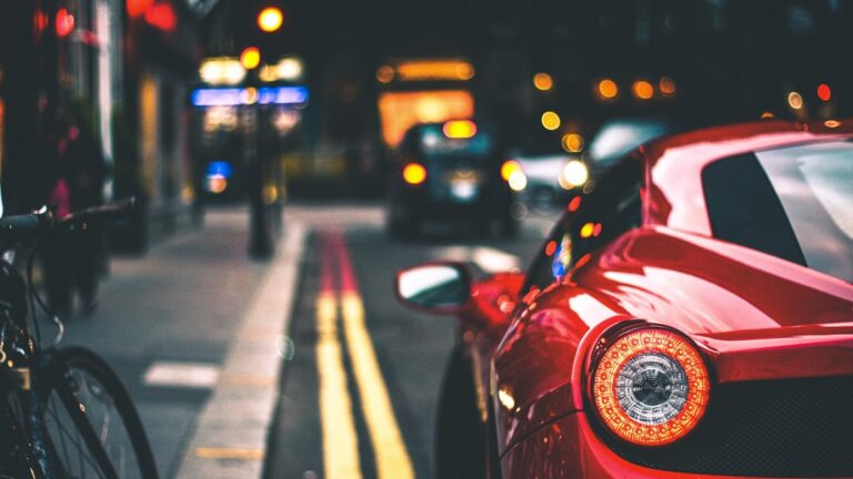 Blurred city street with a red sports car and evening traffic