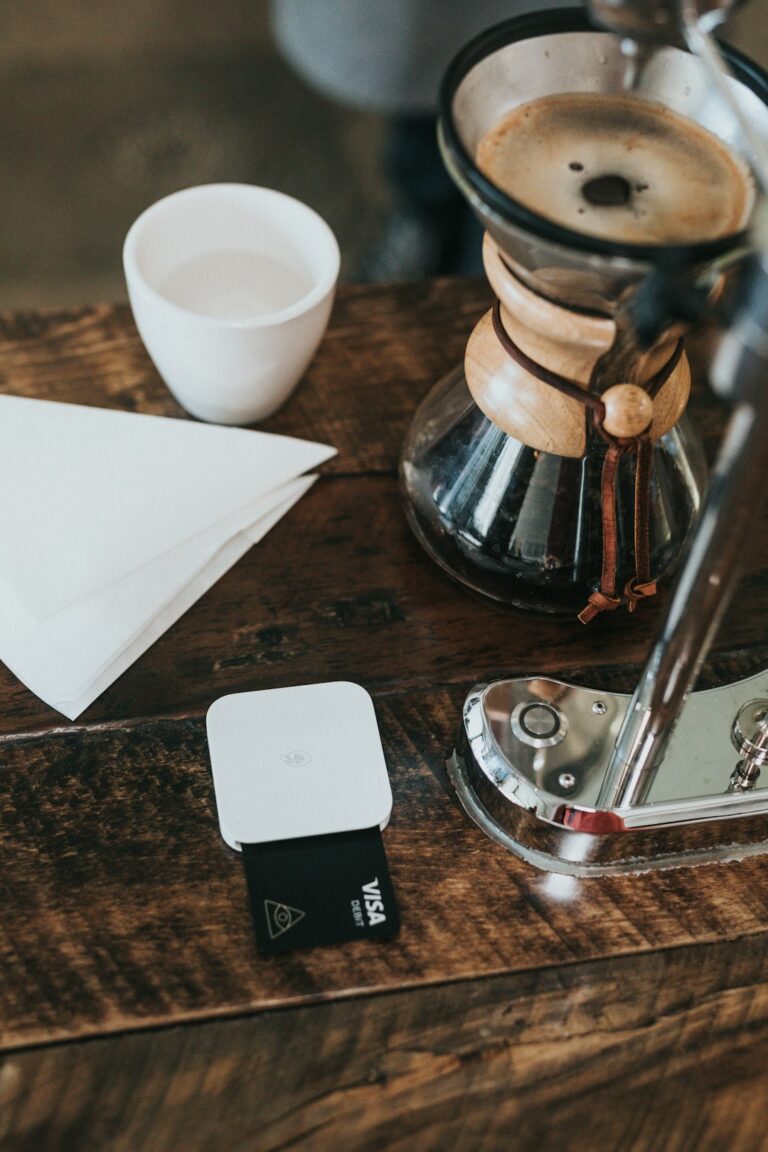 Visa debit card being used for payment at a local coffee shop next to a coffee brewing setup.