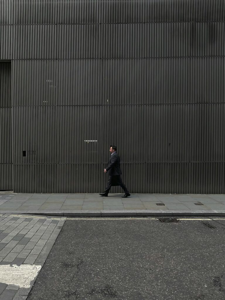 Businessman walking by a modern, ribbed metal building in urban setting