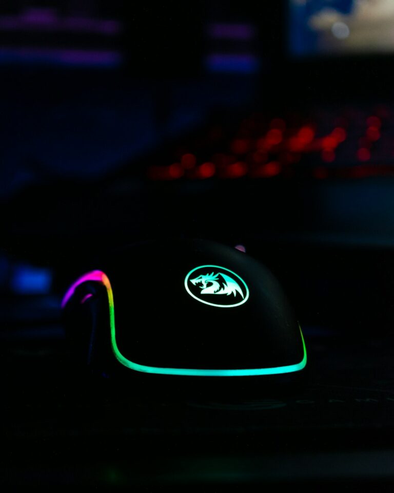 Close-up of an AMD branded gaming mouse illuminated with colorful LED lights in a dark room