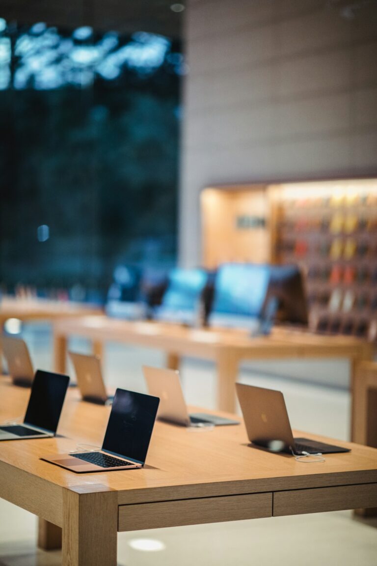 MacBooks on display in an Apple Store with blurred background of other Apple products