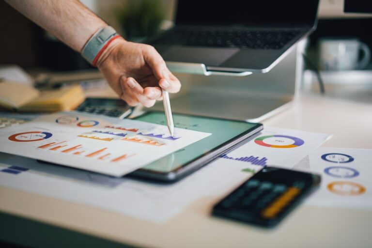 Hand pointing at financial graphs with a pen, showcasing budget airline financial strategies