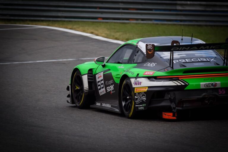 A green race car with various logos speeding on a track.