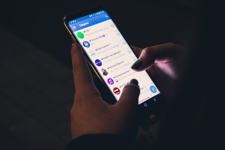 Close-up of a person using a smartphone to access a sports app in a dark environment