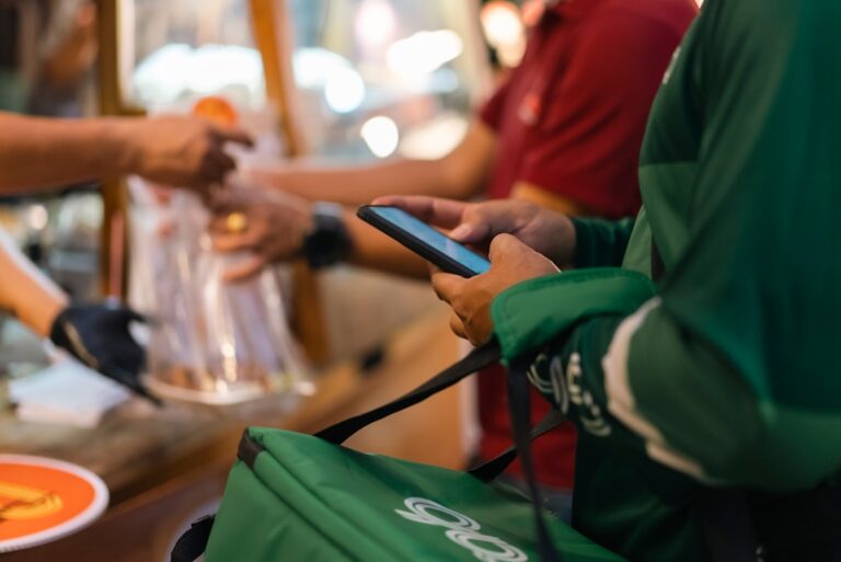 Delivery driver checking phone at a restaurant pickup counter