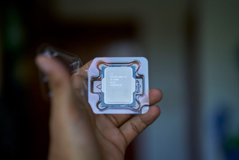 A hand holding an Intel processor chip in packaging, showcasing the company's advanced technology.