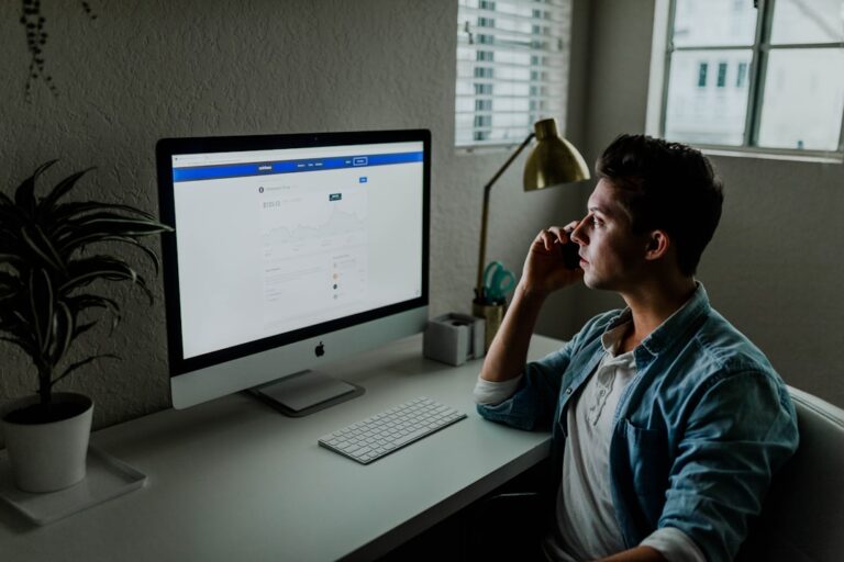 Investor reviewing stock market trends on a computer screen and talking on the phone