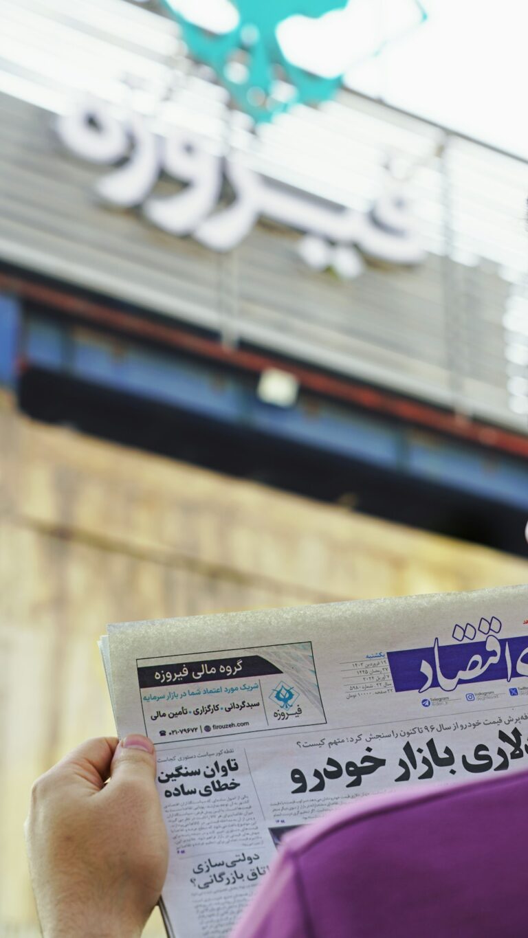 Person reading a newspaper with financial updates in front of a building