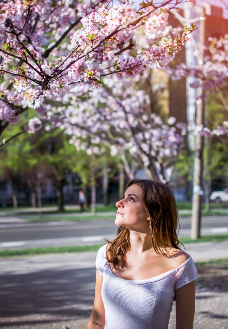 Woman looking up at cherry blossoms in a park