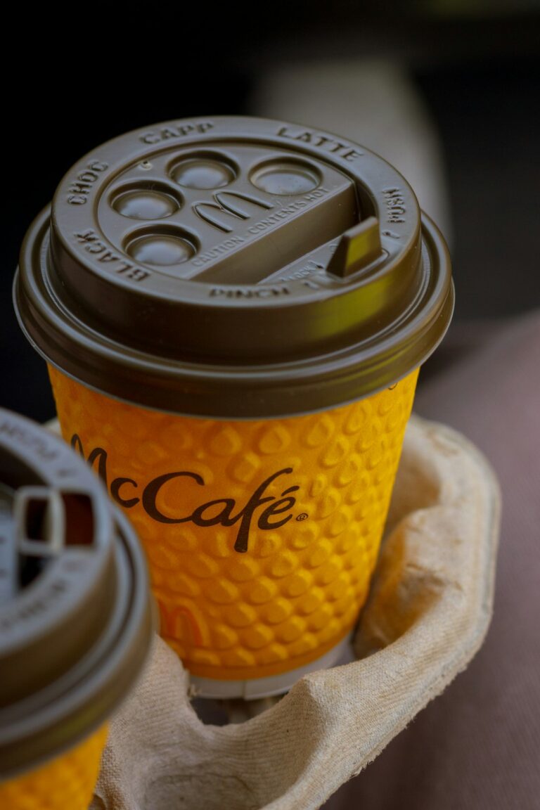 Close-up image of McDonald's McCafé coffee cup in a yellow textured sleeve and brown lid.