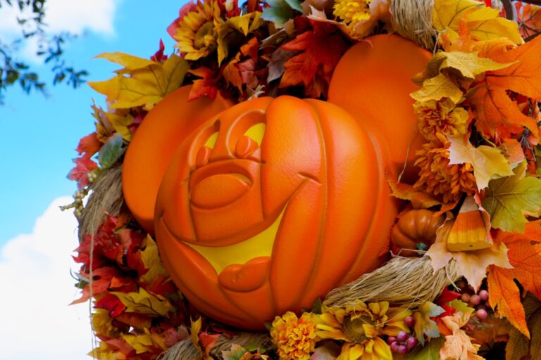 Close-up of a Mickey Mouse jack-o’-lantern surrounded by autumn leaves and flowers at Disney World