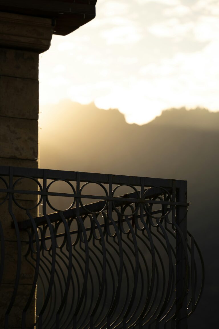 Ornate railing with mountain scenery and sunrise in the background