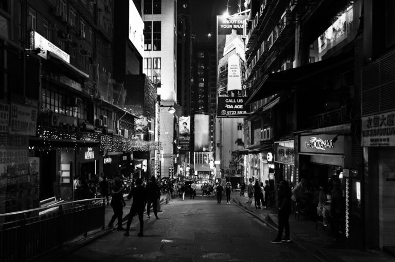 Street view of a bustling city at night with illuminated signs and people walking