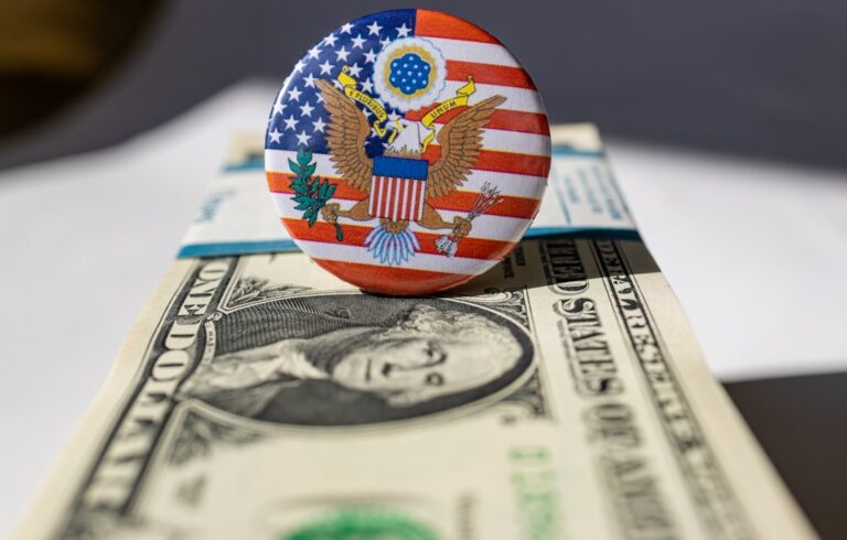 Close-up image of US dollar bills and a button with the American flag and seal.