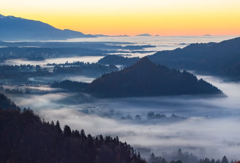 Mist-covered mountains and valleys illuminated by the rising sun.