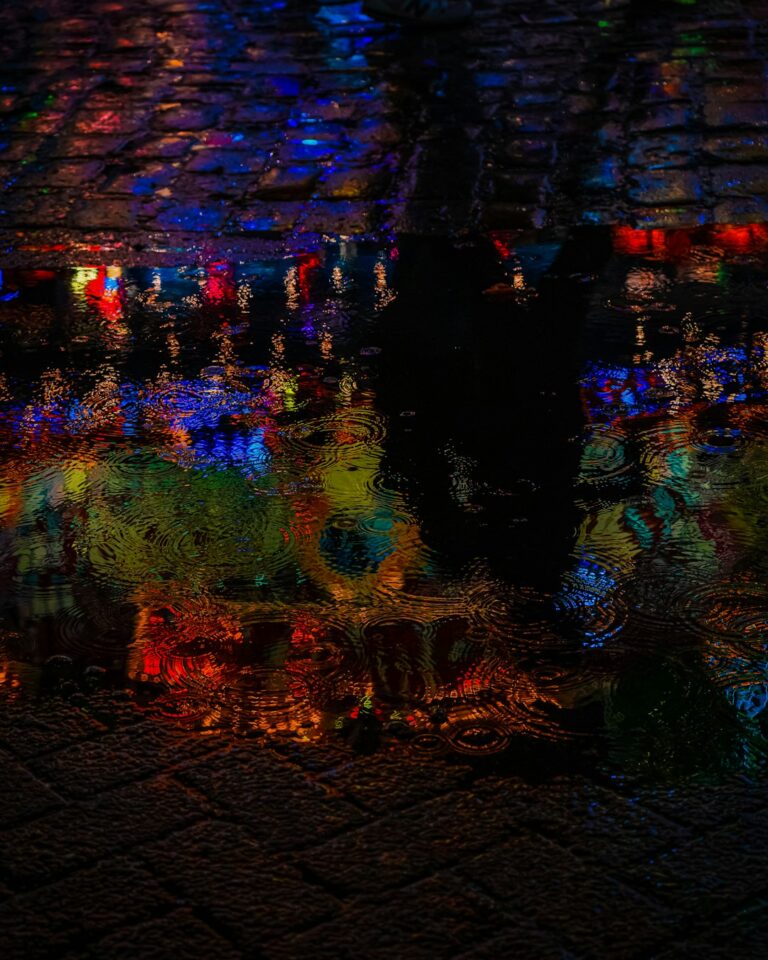 A vibrant reflection of neon lights on a wet cobblestone street captured at night