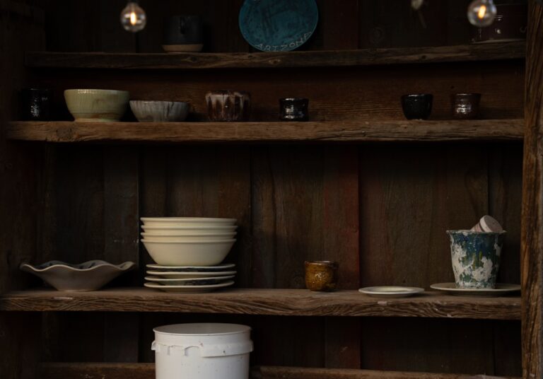 Various pottery items placed on rustic wooden shelves.