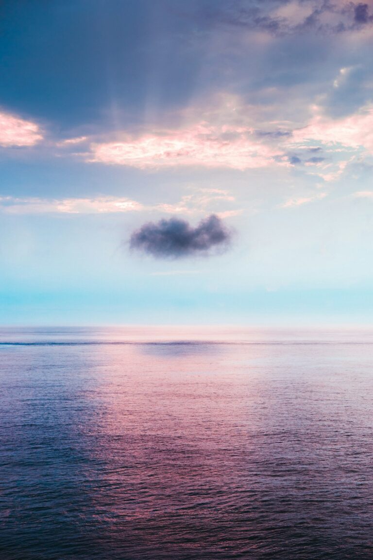 Serene view of the South China Sea with a single dark cloud under a colorful sunset sky