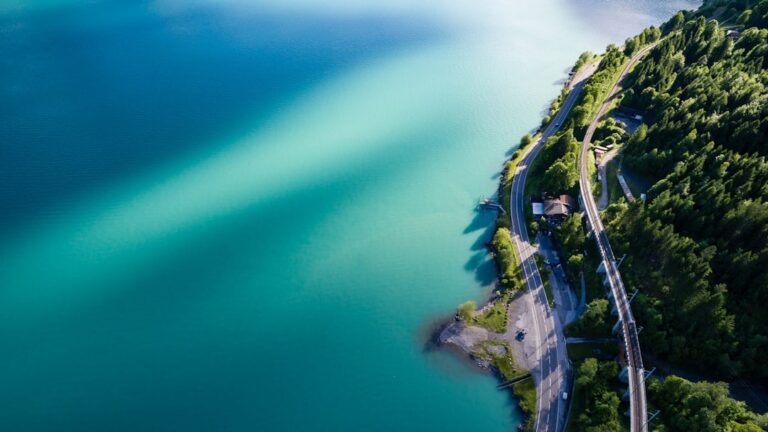 Aerial view of a serene Swiss lake with adjacent winding road and lush greenery