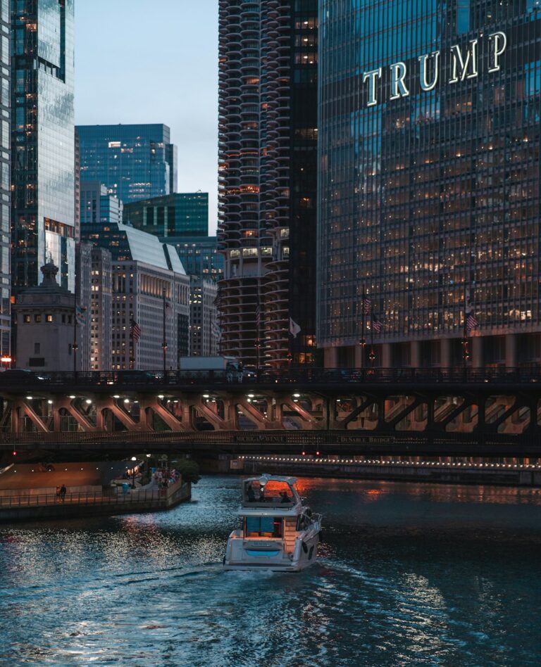 Trump Tower in Chicago with a boat in the river below, showcasing the illuminated city skyline during the evening